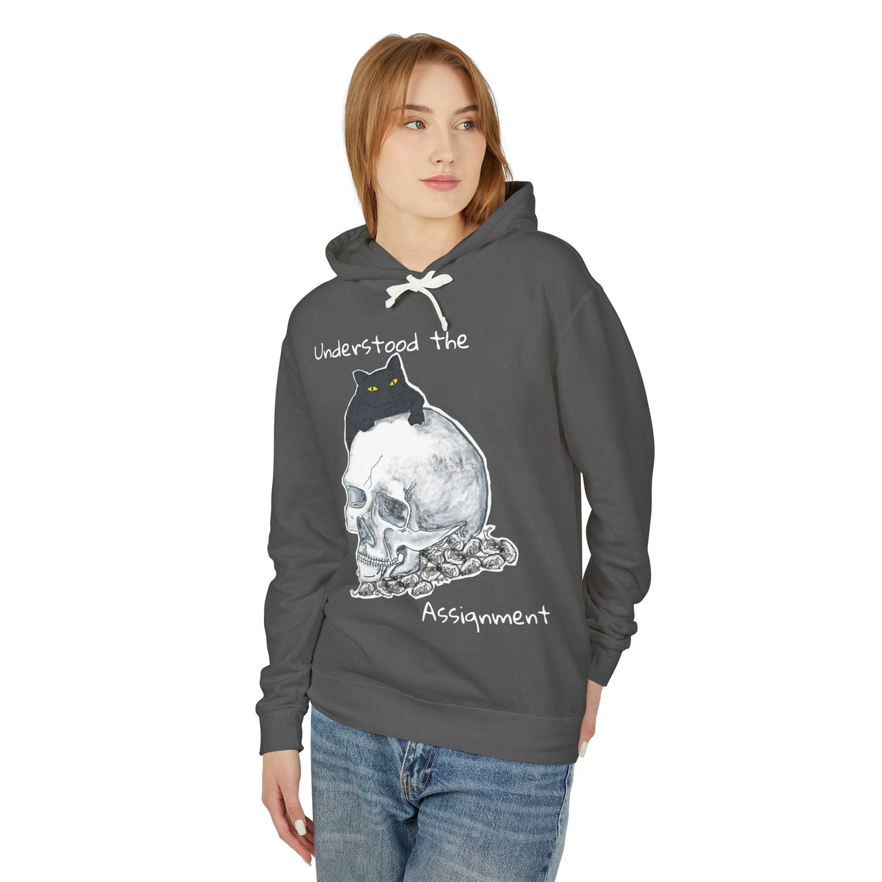 model wearing a grey hoodie with a skull and a black cat on it. It also says "Understood the Assignment"