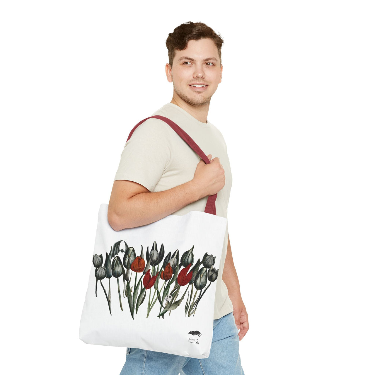 Model carrying a white tote bag with a gothic floral design and red handle.