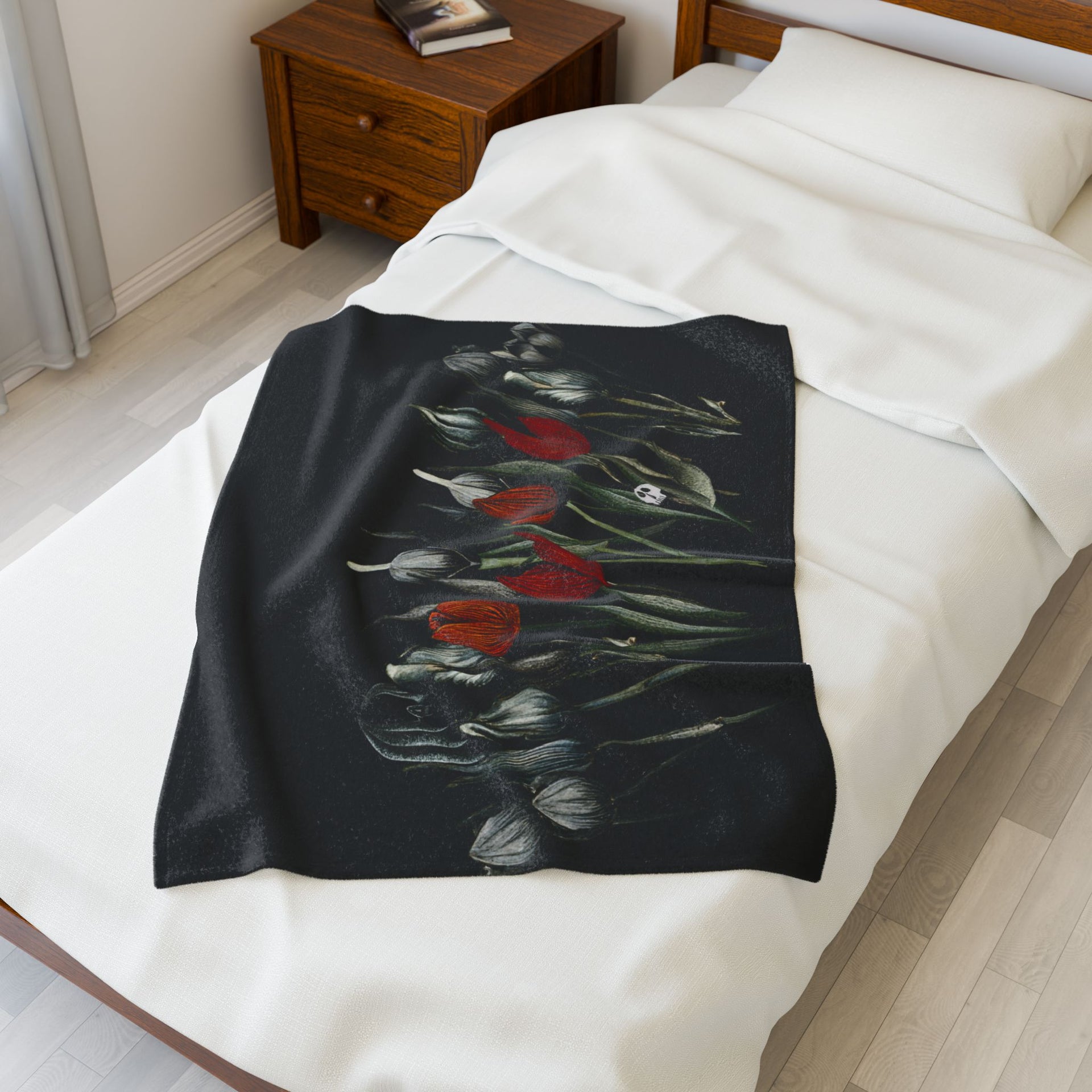 The room features a small wooden bed with a white sheet and pillow, elegantly dressed with the Printify Gothic Floral Velveteen Plush Blanket in black. A wooden nightstand with books complements the light flooring and curtains, enhancing the gothic elegance.